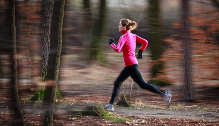 Young woman running outdoors in a city park on a cold fall/winter day